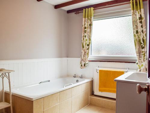 a bathroom with a bath tub and a window at Ty Lewis Cottage in Llanelli