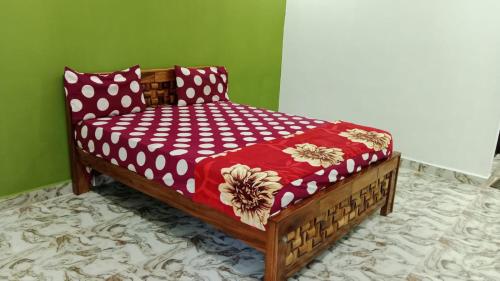 un letto in legno con piumone rosso e bianco di Le Grace Kovalam a Chennai