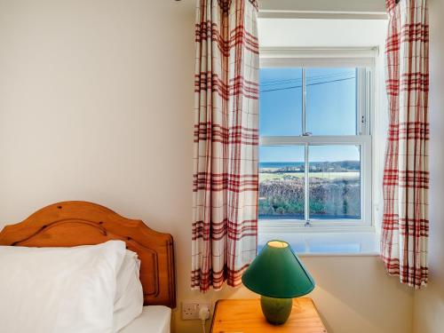 a bedroom with a bed and a window at Dovecoat Cottage in Embleton