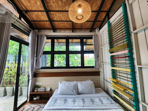 ein Schlafzimmer in einem winzigen Haus mit einem Bett und Fenstern in der Unterkunft Baan Mai Kradan Hostel Chiang Rai in Chiang Rai