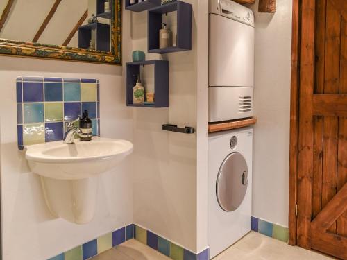 a bathroom with a sink and a washing machine at The Parlour in Hadlow Down