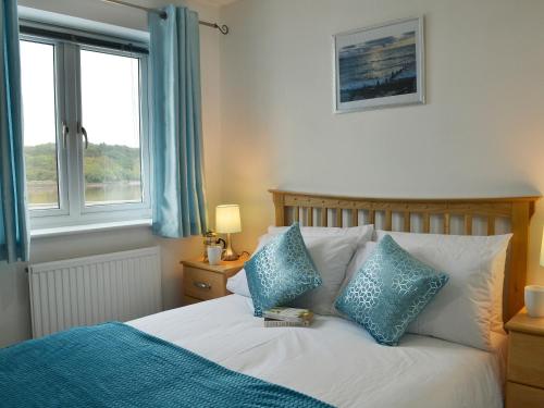 a bedroom with a bed with blue pillows and a window at Mariners Rest in Bideford