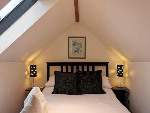 a bedroom with a bed with white sheets and two lamps at Blue Charm in Damerham