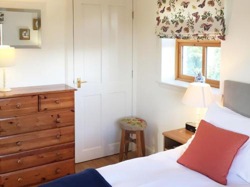 um quarto com uma cama, uma cómoda e uma janela em The Wee House em Muthill