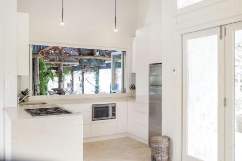 a kitchen with white cabinets and a large window at Wembley House, Southern Highlands in Berrima