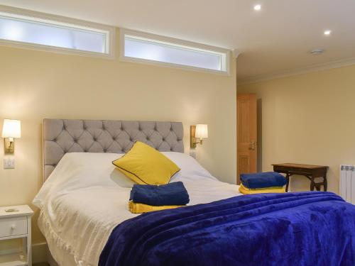 a bedroom with a large bed with blue sheets and two windows at Duck Cottage in Winterbourne Dauntsey