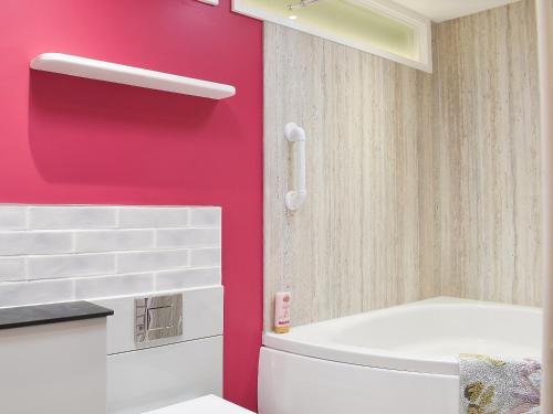 a bathroom with a toilet and a red wall at Duck Cottage in Winterbourne Dauntsey