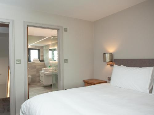 um quarto com uma cama branca e uma casa de banho em The Oyster em Turnchapel