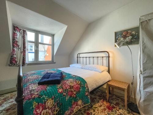 a bedroom with a bed and a lamp and a window at Fishermans Cottage in Gardenstown