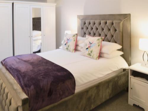 a bedroom with a large bed with a headboard and pillows at Morpeth Court in Morpeth