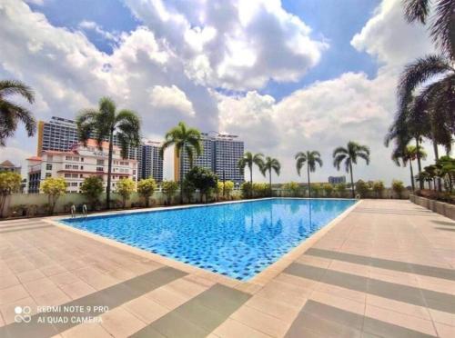 ein großer Pool mit Palmen und Gebäuden in der Unterkunft Duplex Condo Sec 14 Shah Alam in Shah Alam