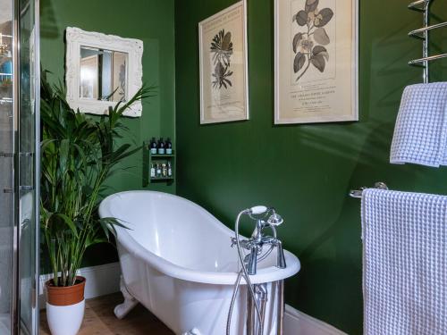 baño verde con bañera y pared verde en The Old Pharmacy, en Narberth