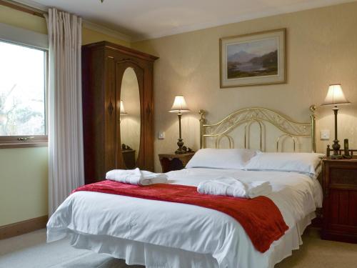 a bedroom with a large bed with towels on it at Rowan Cottage in Aviemore