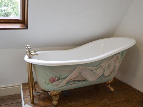 a bath tub with a painting on it in a bathroom at Bakers Cottage in Hotham