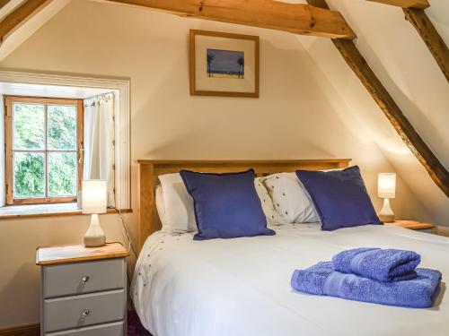 a bedroom with a large bed with blue pillows at The Thatched Cottage in St Andrews