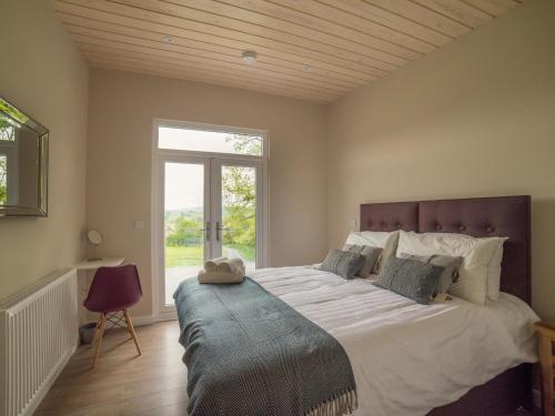 a bedroom with a large bed with a large window at Barn Owl Lodge-qu7487 in Highgate
