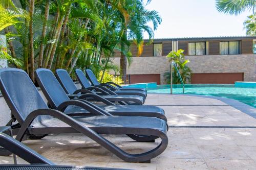 uma fila de cadeiras sentadas ao lado de uma piscina em Mirage Whitsundays em Airlie Beach