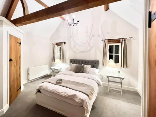 a white bedroom with a large bed and two windows at The Old Stables 1 in Winterslow