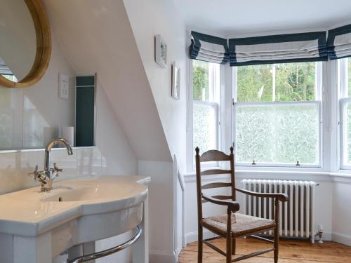 uma casa de banho com um lavatório e uma cadeira ao lado de uma janela em Fircliff - The House On Bute em Port Bannatyne