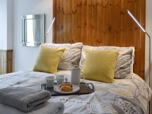 a bed with a tray with a breakfast on it at Old Brewery Cottage - S4576 in Ellanbeich