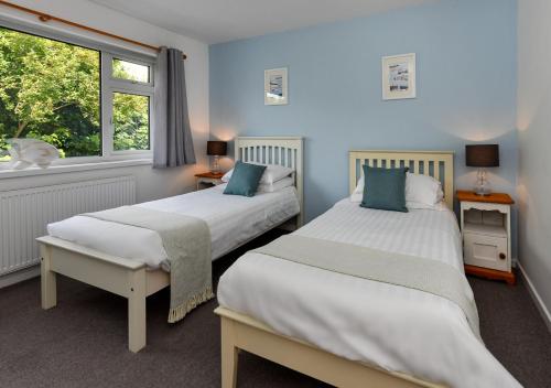 two beds in a room with a window at Llys Neigwl in Abersoch