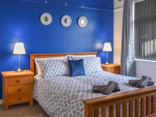 a bedroom with a bed with blue walls and two lamps at Hill View in Preston