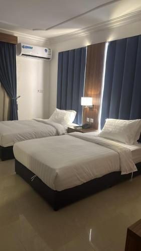 two beds in a hotel room with blue curtains at ريف الشاطئ للشقق الفندقية in Dammam