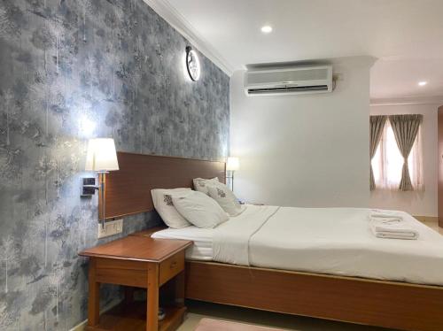 een slaapkamer met een bed en een tafel met een klok aan de muur bij Kings Hotel Egmore in Chennai