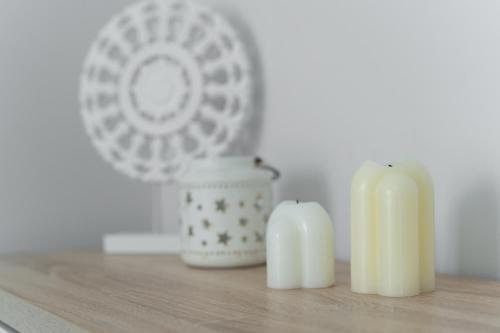 two white candles sitting on a table with a fan at Apartament Doris 2 - 50 m do plaży in Pobierowo