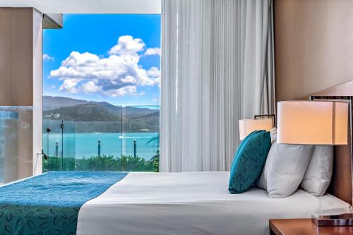 a bedroom with a bed and a large window at Mirage Whitsundays in Airlie Beach