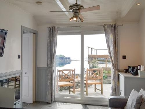 a living room with a ceiling fan and a sliding glass door at Misty Isles Cottage - S4577 in Ellanbeich