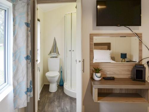 a bathroom with a toilet and a tv on a wall at Ocean Glade - Uk32963 in Corton