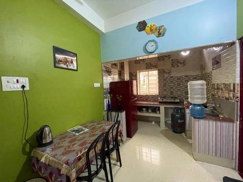 cocina con paredes verdes y mesa con sillas en Veda Homestay en Agartala