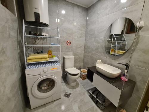 uma casa de banho com uma máquina de lavar roupa e um lavatório em Sovran's dream 2bedroom Apt 10min wak from center em Pristina
