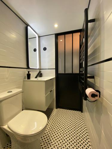 La salle de bains est pourvue de toilettes blanches et d'un lavabo. dans l'établissement La Maison du Pere Pilon avec petit dejeuner, à Auvers-sur-Oise