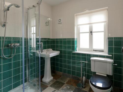 a green tiled bathroom with a toilet and a sink at Gelli Hir in Bronant