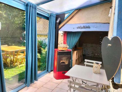 cocina con fogones y mesa y algunas ventanas en Charmante maisonnette en pierre, en Écardenville-sur-Eure