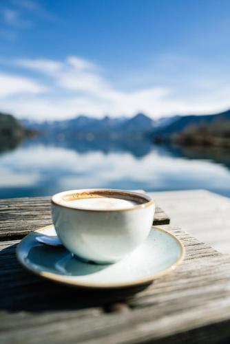 a cup of coffee sitting on top of a wooden table at Villa Alma - a lakeside Boutique Hotel in Sankt Gilgen