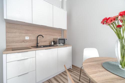 a kitchen with white cabinets and a table with a vase of flowers at Apartament Doris 2 - 50 m do plaży in Pobierowo