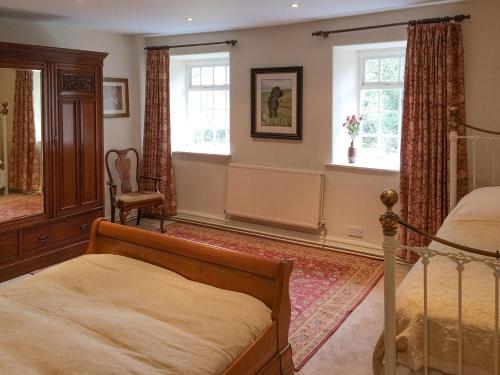 a bedroom with a bed and two windows at Inglenook Cottage in Kettlewell