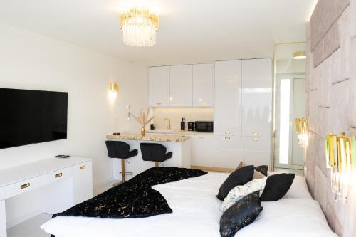 Biały pokój z łóżkiem i kuchnią w obiekcie Penthouse apartments MINI s privátnou vírivou vaňou w Trzcianie
