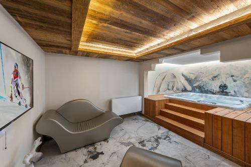 a bathroom with a tub and a chair in it at Le Cheval Blanc Luxe, skis aux pieds, jacuzzi, hammam, salle de cinéma in Les Allues