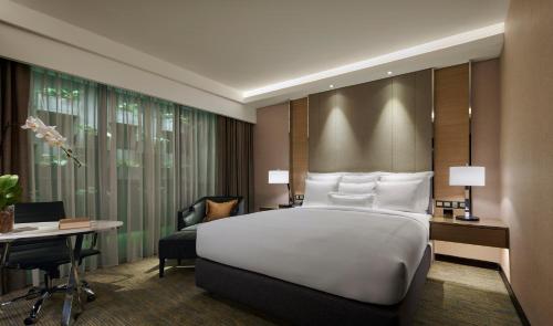 JW Marriott Kuala Lumpur في كوالالمبور: غرفة نوم مع سرير أبيض كبير ومكتب