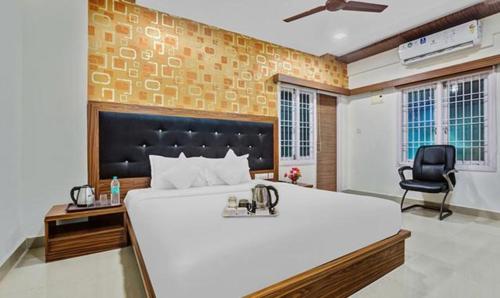um quarto com uma grande cama branca e uma cadeira em FabHotel Luck Inn Residency em Chennai