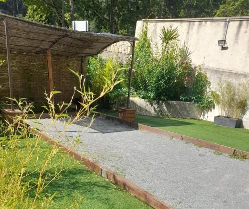a garden with a stone walkway and a building at Hôtel Les Alizés in Puget-Théniers
