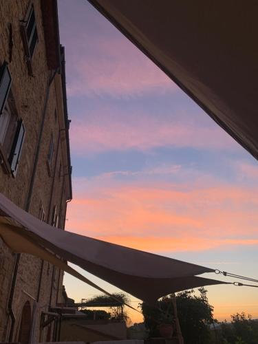a white umbrella in front of a building with a sunset at Casa Cerboneschi in Casale Marittimo