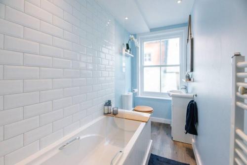 a bathroom with a tub and a toilet and a window at Seaway Cottage, Aldeburgh in Aldeburgh