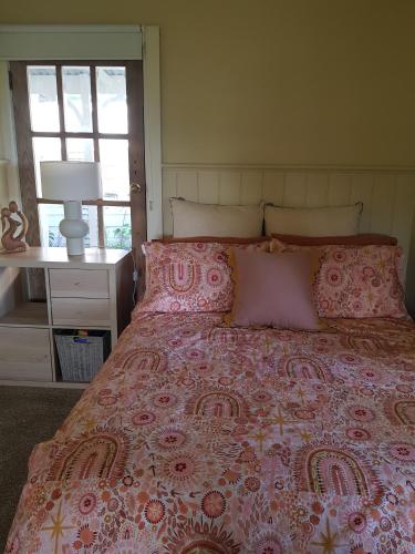 a bedroom with a pink bed with pillows at Foster - Nature Retreat - Nippards Nature Cottage in Boolarong