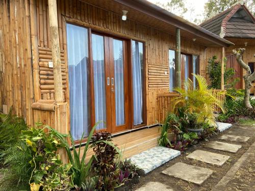 a wooden house with a door and some plants at D'Yoga Bamboo Cabin in Kintamani