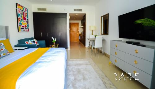 a bedroom with a bed with a tv and a dresser at Rare Holiday Homes welcomes you in - Canal View - The links canal Apartment R304 in Dubai